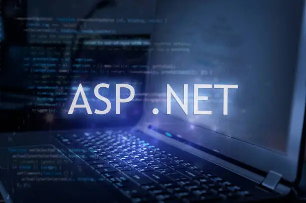 Photo of ASP .NET inscription against laptop and code background. Learn dot net programming language, computer courses, training.