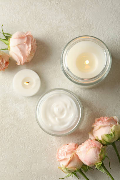 istock Scented candles, cosmetic cream and roses on white table 1290100678