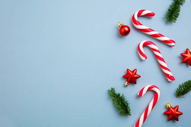 istock White and red candy canes and Christmas tree decorations over blue background. 1290101445