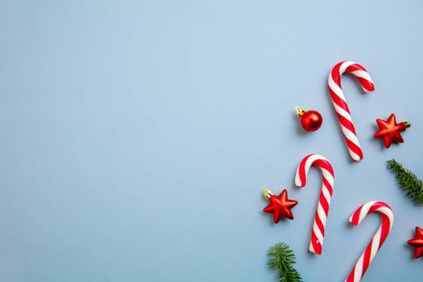 istock White and red candy canes and Christmas tree decorations over blue background. 1290101447