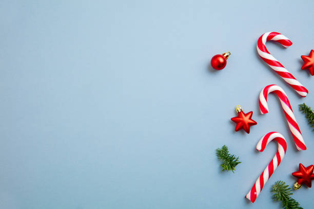 istock White and red candy canes and Christmas tree decorations over blue background. 1290101452