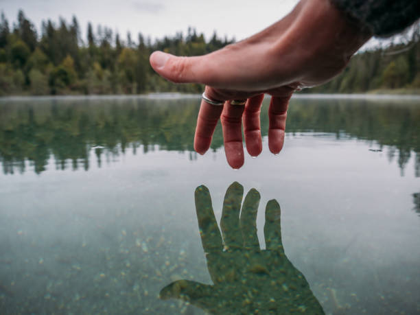 istock Woman's hand touches surface of alpine lake 1290101456