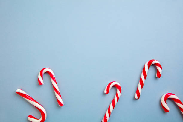 istock White and red candy canes and Christmas tree decorations over blue background. 1290101457