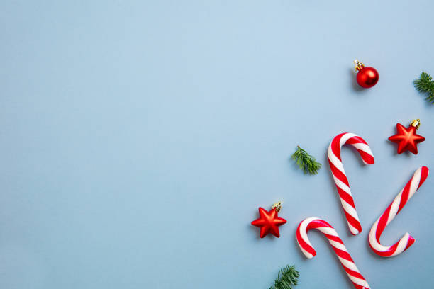 istock White and red candy canes and Christmas tree decorations over blue background. 1290101463