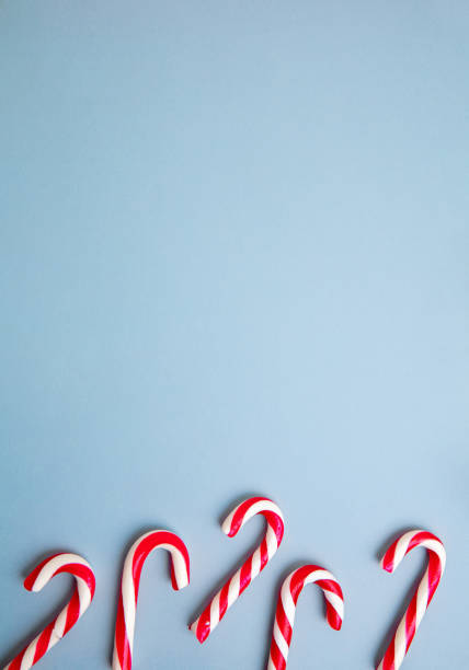istock White and red candy canes and Christmas tree decorations over blue background. 1290101464