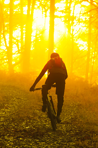 Man cycling with mountain bike at sunrise or sunset - focus on the man