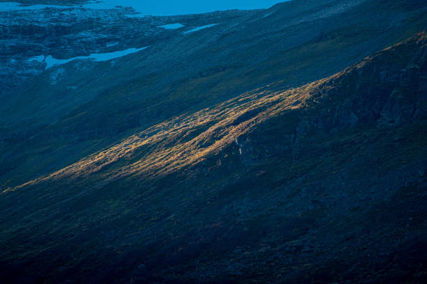 istock Patch of sunlight shining down on a mountain slope. 1290101986