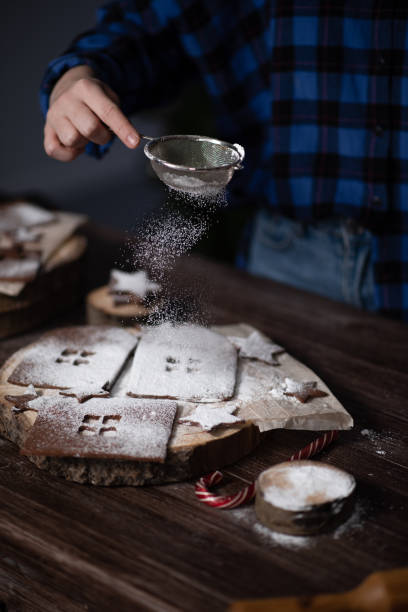 istock Hands sprinkle gingerbread cookies with powdered sugar through a strainer. 1290102982