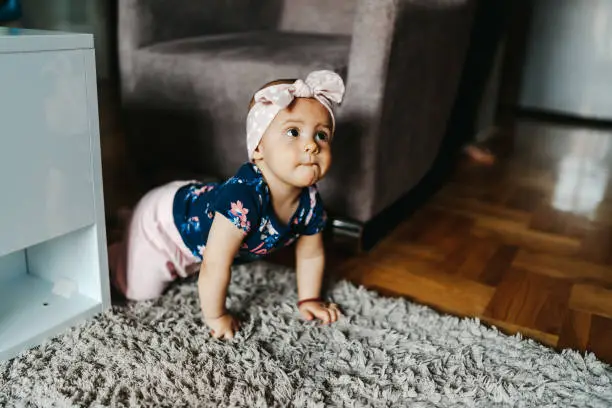 Cute baby girl crawling on floor at home in a playroom