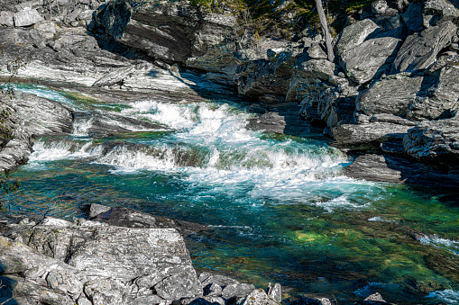 Wild and fast moving river rapids white water rushing over rugged cliffs. Close up.