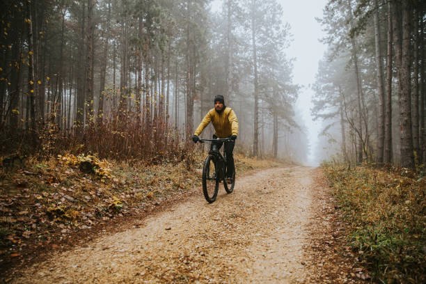 istock Young man biking through autumn forest 1290105336