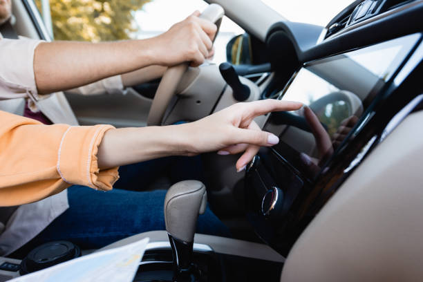 istock Cropped view of woman using audio system in car while husband driving on blurred background 1290106409