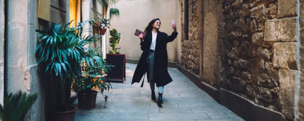 istock Carefree Caucasian vlogger enjoying walking sightseeing around ancient streets using cellphone front camera for shooting online streams translation, pretty influencer making selfie video vlog 1290106571