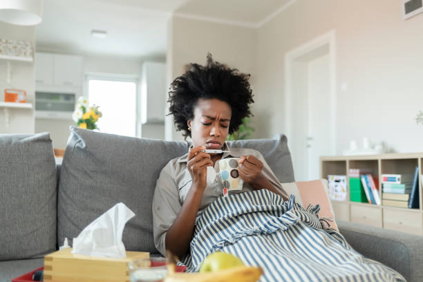 Woman Reading Her Temperature on a Thermometer at Home