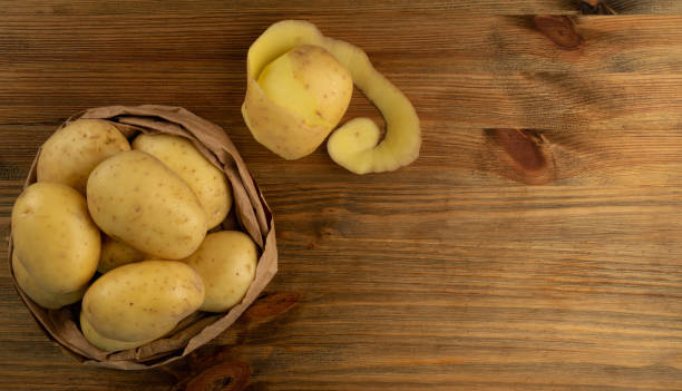 istock Raw Peeled Potatoes on Wooden Cutting Board Background 1290113872