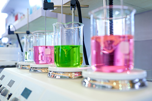 Close-up of stirring multi-color liquid at beaker in laboratory.