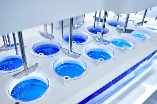 Close-up of automatic stirring blue reagent in group of beakers in laboratory.