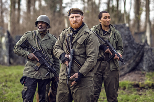 A redhead military male soldier, a black captain and female agent during an outdoor operation in the autumn