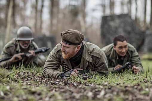 A redhead military male soldier, a black captain and female agent during an outdoor operation in the autumn