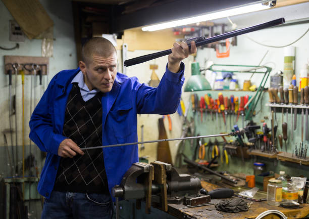 istock Qualified gunsmith using ramrod to cleaning shotgun barrel 1290122244