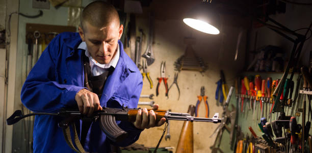istock Gunsmith with Kalashnikov assault rifle in weapons workshop 1290122265