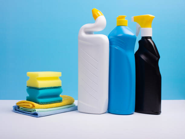 istock Cleaning concept with various plastic bottles canisters and sponges on blue background. Various detergents and the necessary attributes for cleaning 1290122882