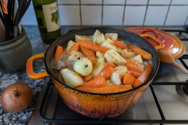 Orange casserole with meat, diced potatoes, carrots and celeriac on gas stove. stock photo
