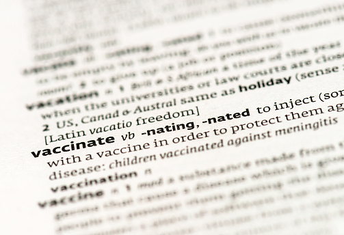 A macro image of the word 'vaccinate' in a dictionary definition.