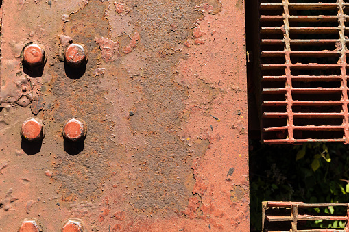 Rusting section of a gray metal pipe on a sunny morning.