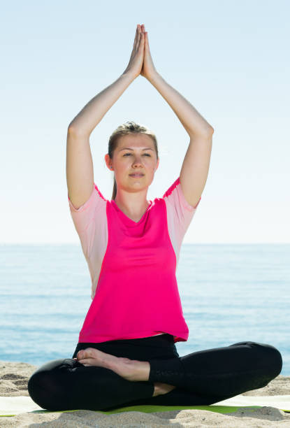 istock Girl practicing yoga poses on beach 1290132312