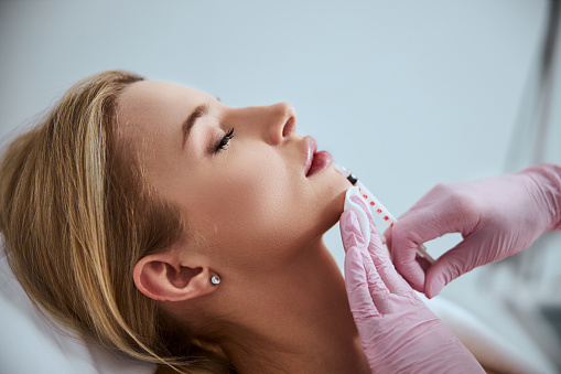 Side view of a woman undergoing the lip augmentation procedure done in a beauty salon