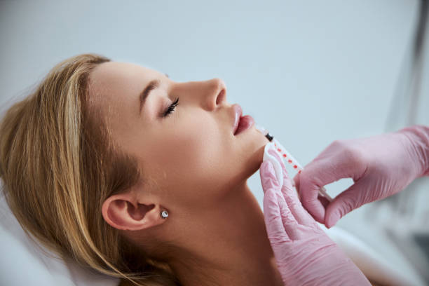 Professional cosmetologist injecting a dermal filler into the patient lips Side view of a woman undergoing the lip augmentation procedure done in a beauty salon human lips stock pictures, royalty-free photos & images