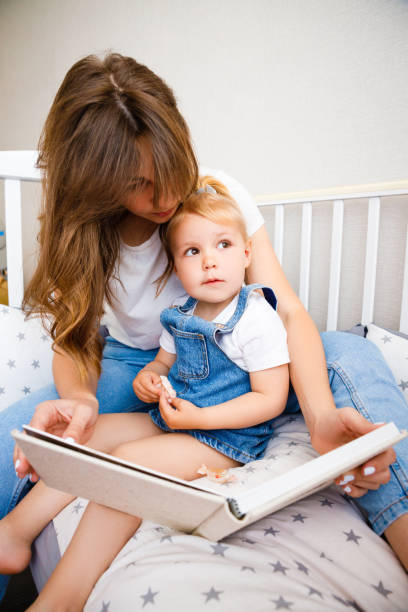 istock Young mother reads a book to her daughter before bedtime. 1290134043