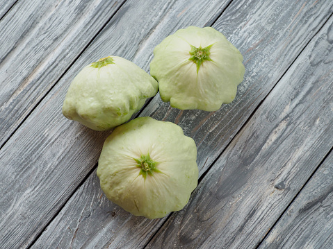 Pattypan squash on old rustic wooden background. Patisson is a fresh organic healthy food. Copyspace for text and top view.