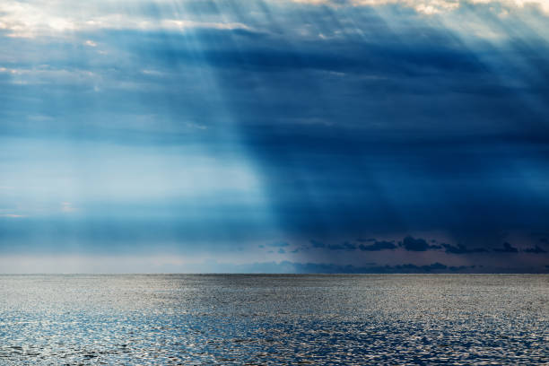 istock A sunbeam dividing the frame in half through dark clouds over the sea with reflection 1290135799