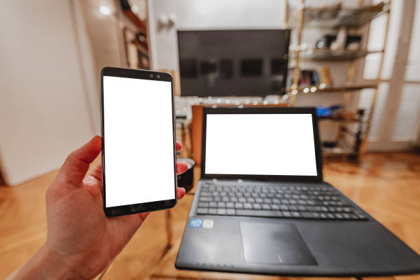 istock Personal perspective on a multiple screens on a mobile phone and laptop at home with a white empty screens. POV 1290137651