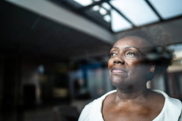 istock Senior woman looking through the window 1290137770