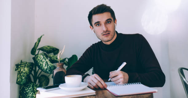 istock Serious businessman writing plans in daily planner while having coffee 1290146823