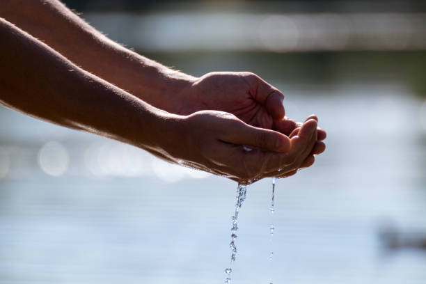 istock Hands dropping river water on bright summer day 1290147400