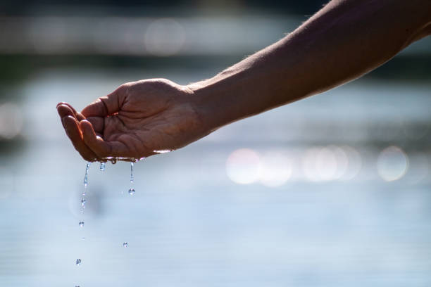 istock Hands dropping river water on bright summer day 1290147470