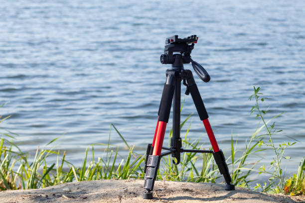istock Camera red tripod standing near lake water setup 1290147485