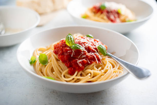 espaguetis con salsa de tomate y albahaca en un plato - salsa de tomate fotos fotografías e imágenes de stock