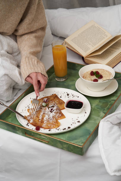 istock Woman reading book while having breakfast in bed. 1290151898