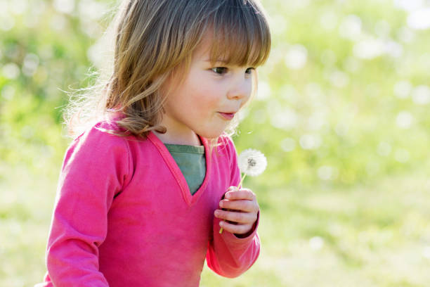 istock cute little girl blowing dandelion 1290157804