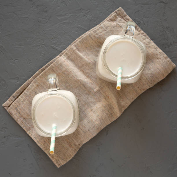 istock Coconut milk in glass jars on a gray surface, top view. Overhead, flat lay, from above. 1290158585