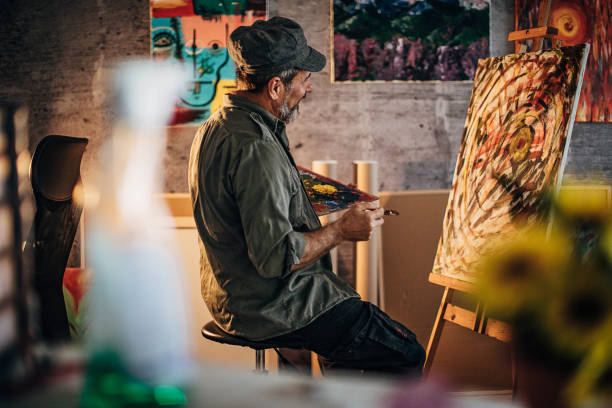 istock Senior male painter painting in his home studio 1290160154
