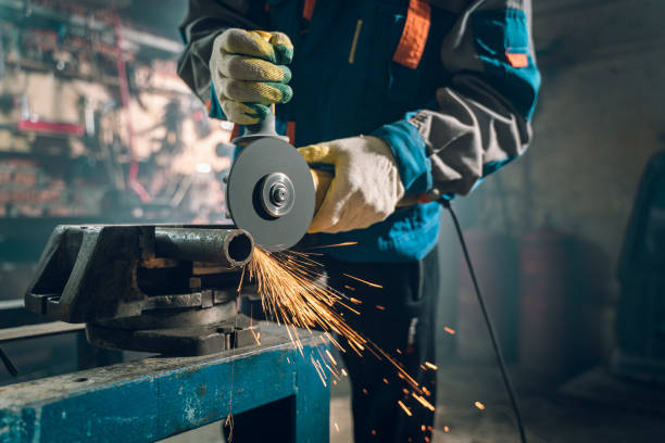 istock Locksmith in special clothes and goggles works in production. Metal processing with angle grinder. Sparks in metalworking 1290162961