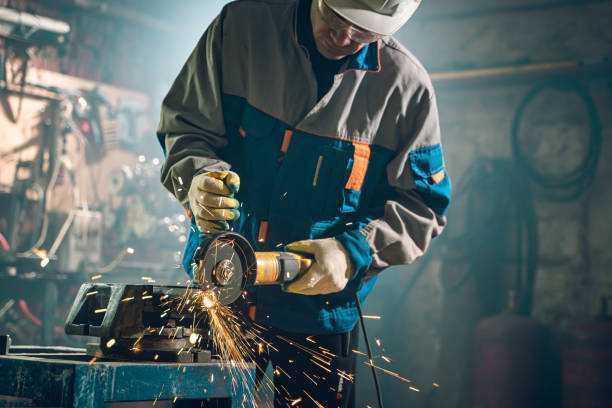 istock Locksmith in special clothes and goggles works in production. Metal processing with angle grinder. Sparks in metalworking 1290162982