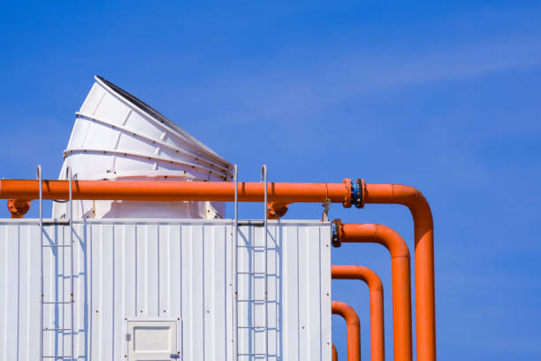 istock Large ventilation chimney with orange pipelines and exhausting machine system on factory building roof 1290163000