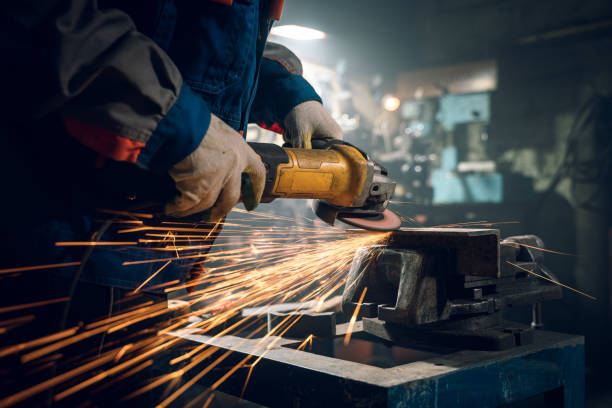 istock Locksmith in special clothes and goggles works in production. Metal processing with angle grinder. Sparks in metalworking 1290163014